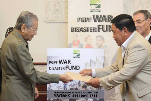 Tan Sri Norian Mai, PGPF Chairman receiving a personal donation on behalf of PGPF from Tun Dr Mahathir at the launch of the War Disaster Fund.The fund was later renamed Criminalise War Fund to cover a wider aspect of humanitarian relief and advocacy works.
